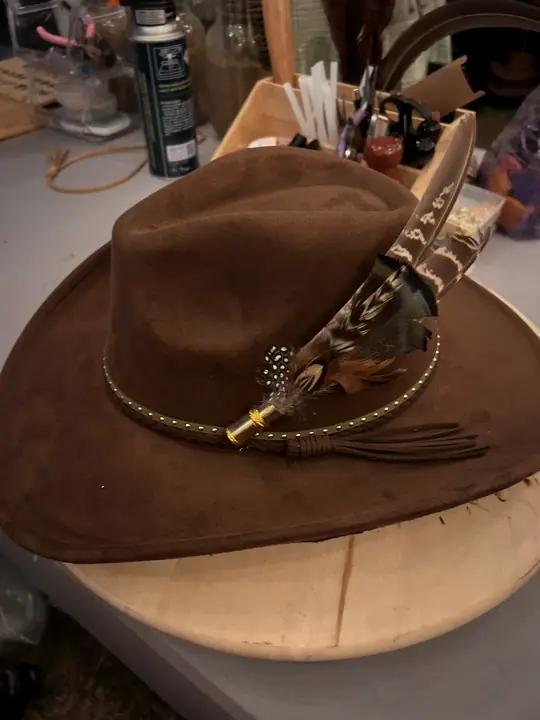 Chocolate hat with studded braid, tassel and feather pick