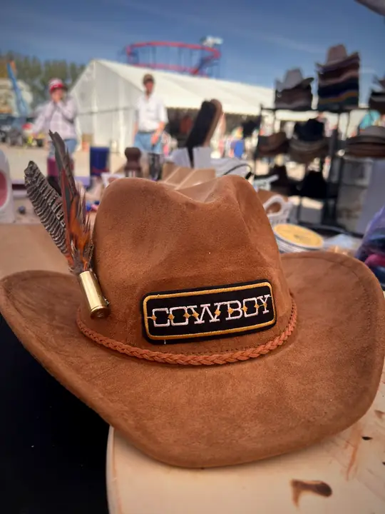 Tan hat with a “Cowboy” patch and feather