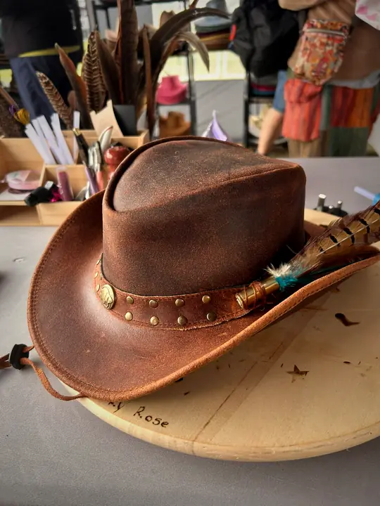 Distressed leather hat with studded band and pheasant feather pick